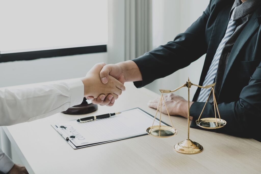 Áreas de Atuação 3 Imagem decorativa, representação do direito em fechamento de contratos. Pessoas apertando as mãos e balaça da justiça na mesa.